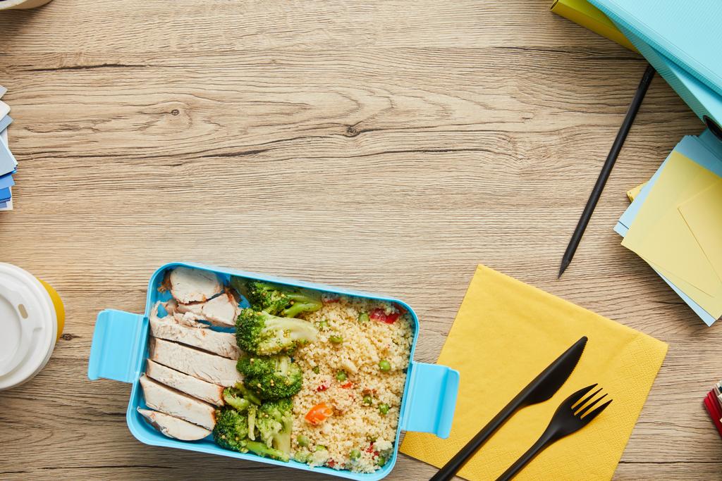 Κορυφαία θέα από πλαστικό κουτί μεσημεριανού γεύματος με ρύζι, μπρόκολο και κοτόπουλο σε ξύλινο τραπέζι - Φωτογραφία, εικόνα