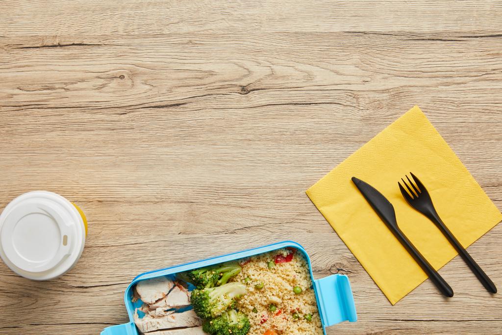 Widok z góry kawy do zrobienia i plastikowe Lunchbox z risotto, brokuły i kurczaka na drewnianym stole - Zdjęcie, obraz