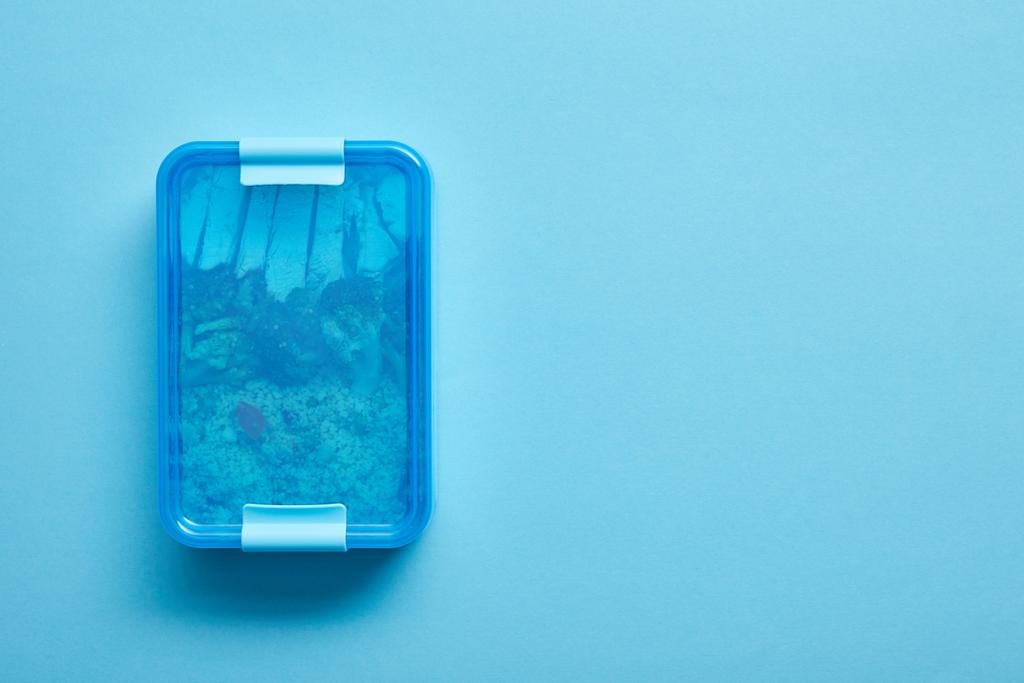 Вид зверху на обідню коробку зі смачною здоровою їжею на синьому фоні
  - Фото, зображення