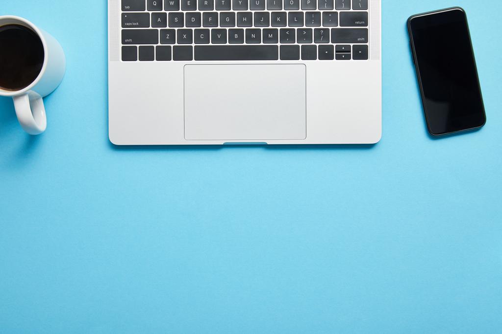 Vista superior del teclado del ordenador portátil, ratón de ordenador, teléfono inteligente y taza de café sobre fondo azul, editorial ilustrativa
 - Foto, imagen