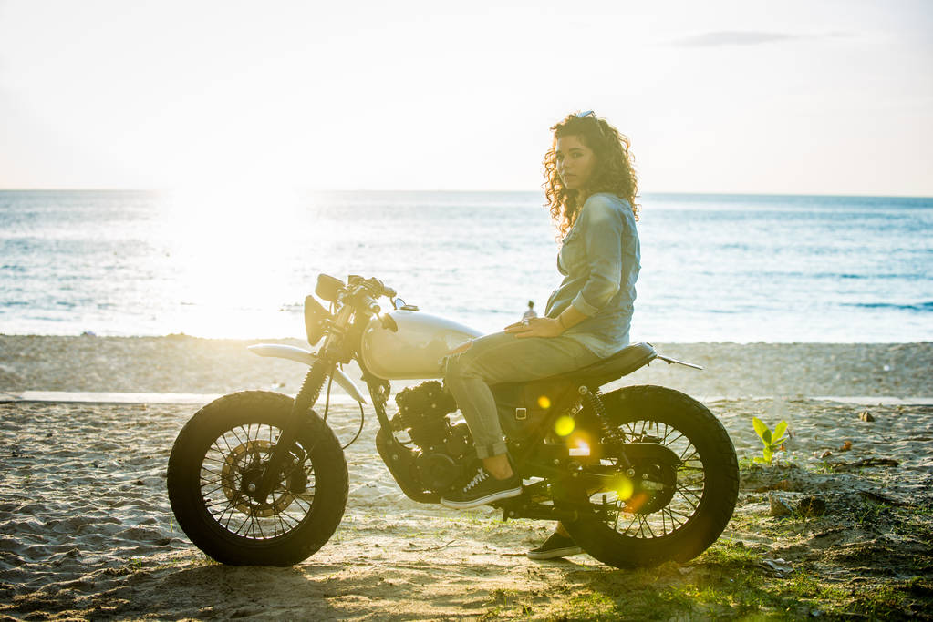 カフェのレーサーバイクを運転する女性バイカー - 写真・画像