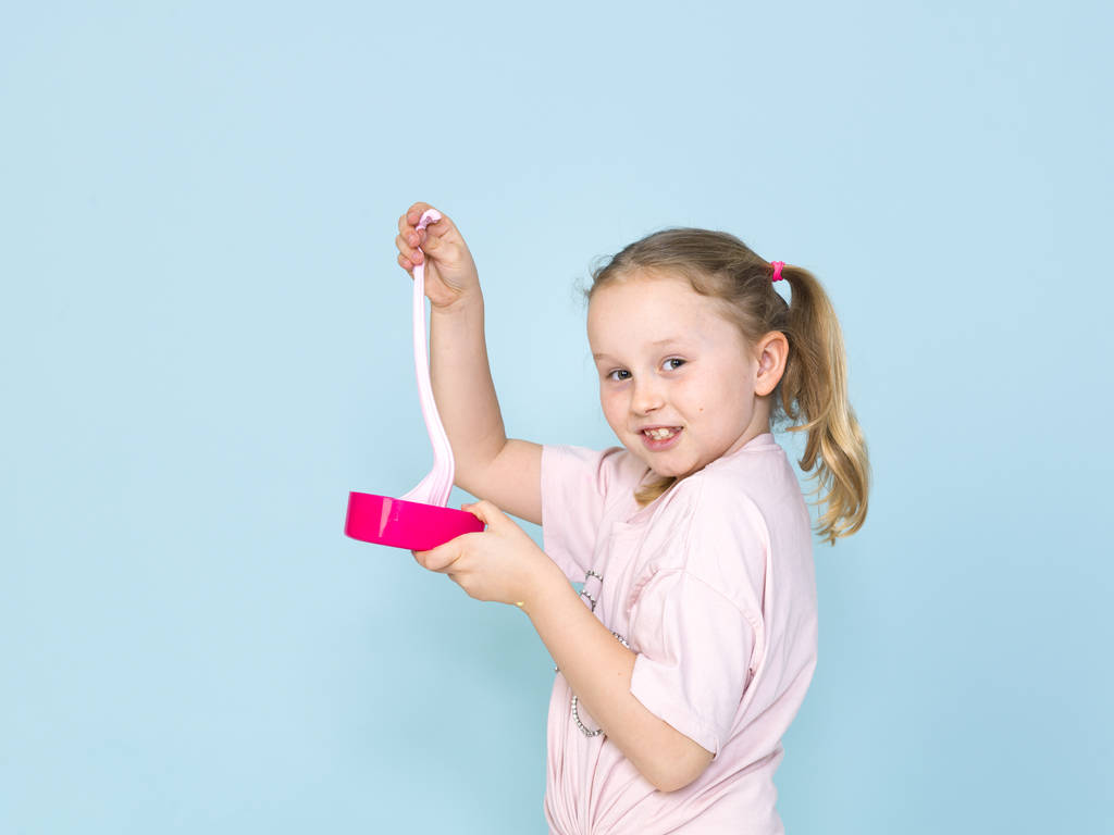 bella bionda bambina che gioca con melma rosa di fronte a sfondo blu
 - Foto, immagini