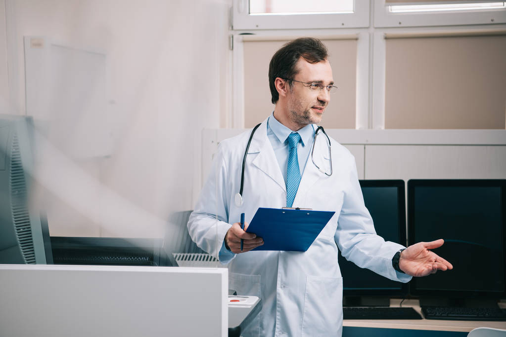selective focus of handsome doctor gesturing while holding clipboard - Photo, Image