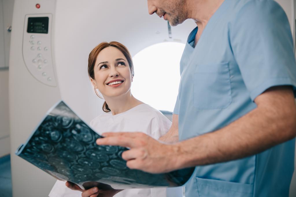 обрізаний вид лікаря, що показує рентгенівський діагноз щасливій жінці
 - Фото, зображення