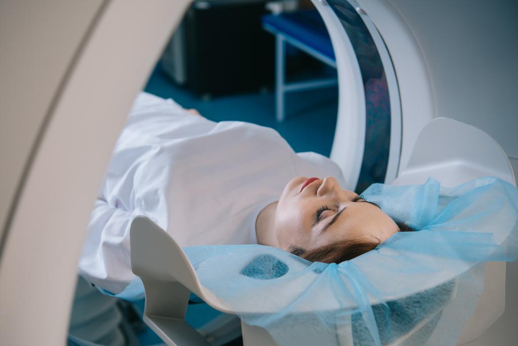 young woman lying on ct scanner bed during tomography diagnostics in hospital - Photo, Image