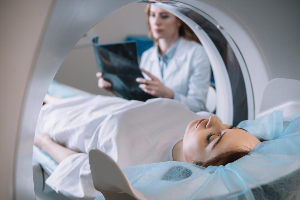 messa a fuoco selettiva del radiologo che tiene la diagnosi a raggi X mentre il paziente sdraiato sul letto dello scanner ct durante la diagnostica
 - Foto, immagini