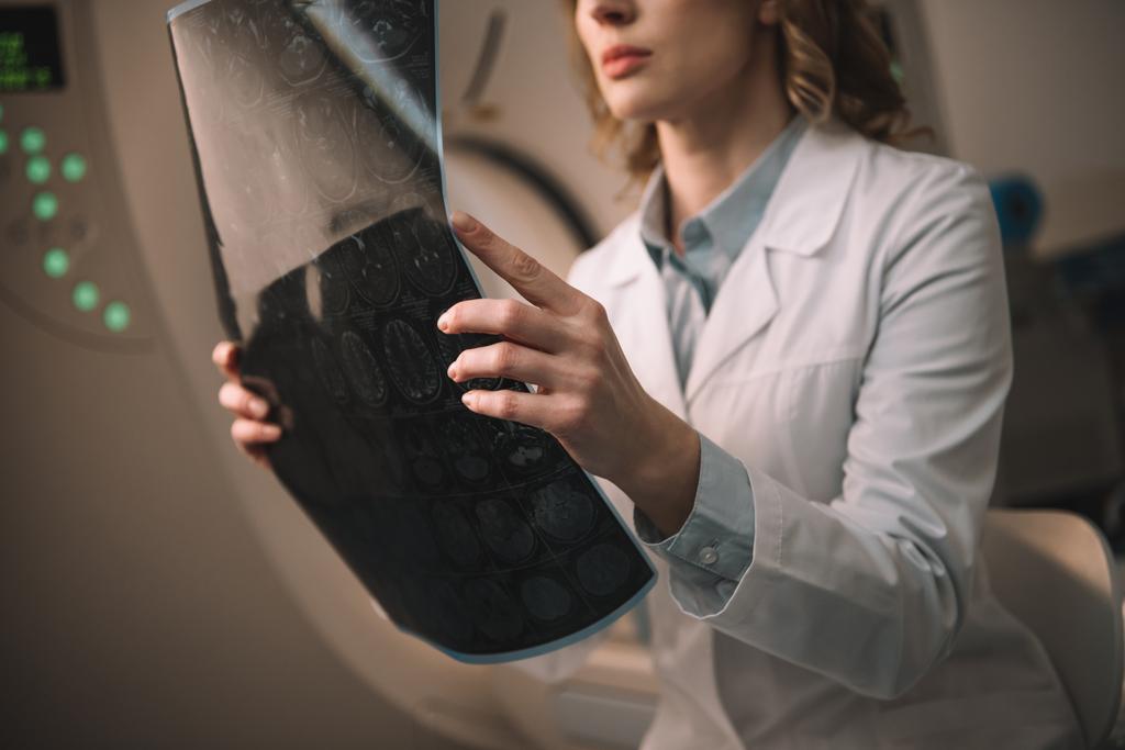 Ausgeschnittene Ansicht eines Radiologen mit Röntgendiagnose im Sitzen am Computertomographen - Foto, Bild
