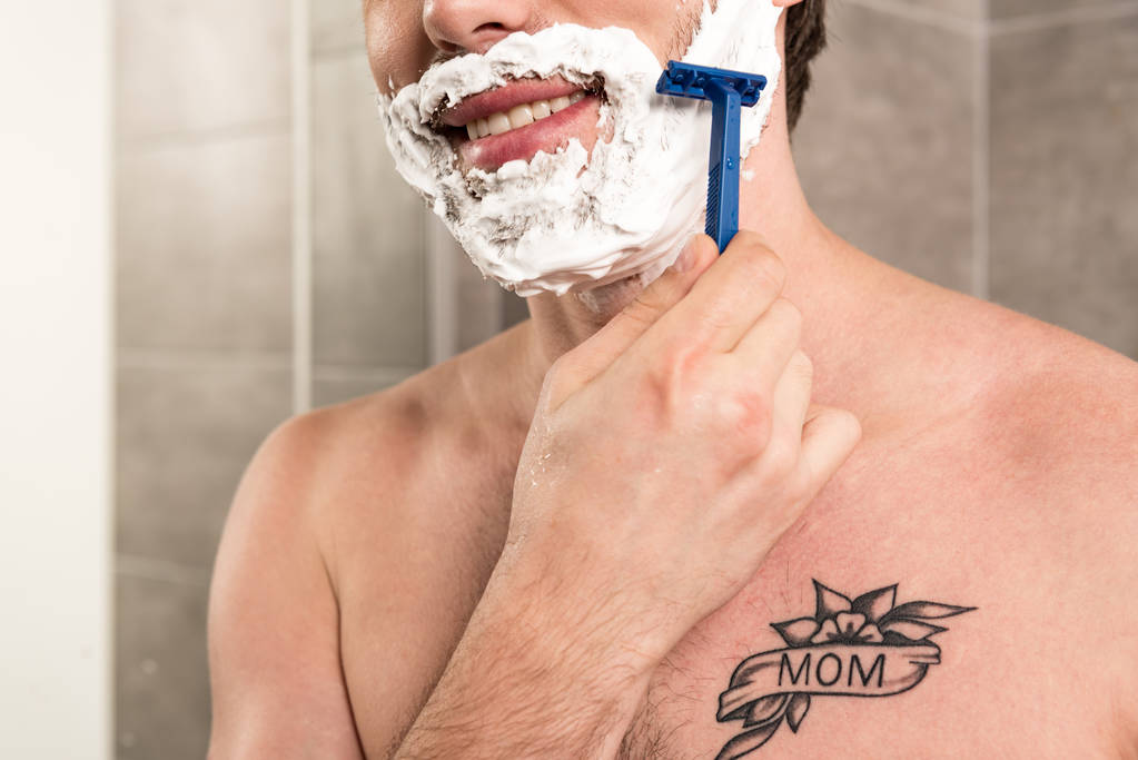 vista cortada de homem sorridente barba de barbear com navalha no banheiro
 - Foto, Imagem