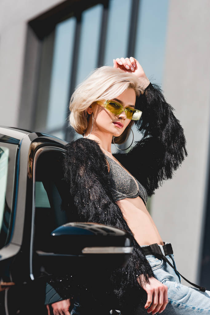hermosa mujer joven con estilo en gafas posando cerca de coche
 - Foto, imagen