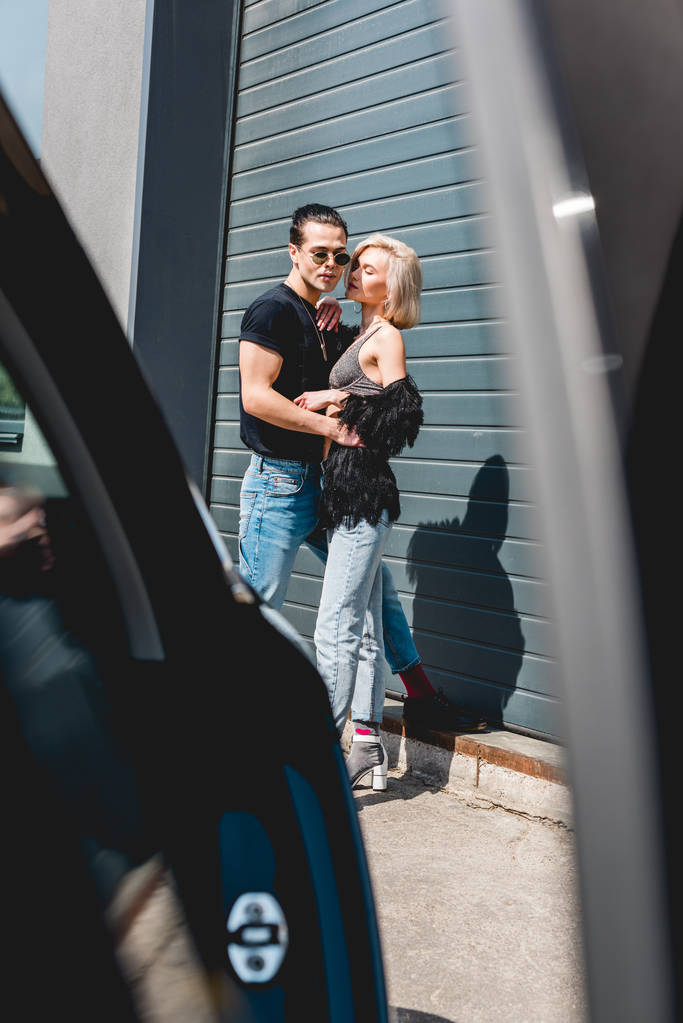 車の近くに美しい女の子を抱きしめるスタイリッシュなハンサムな男の選択的な焦点 - 写真・画像