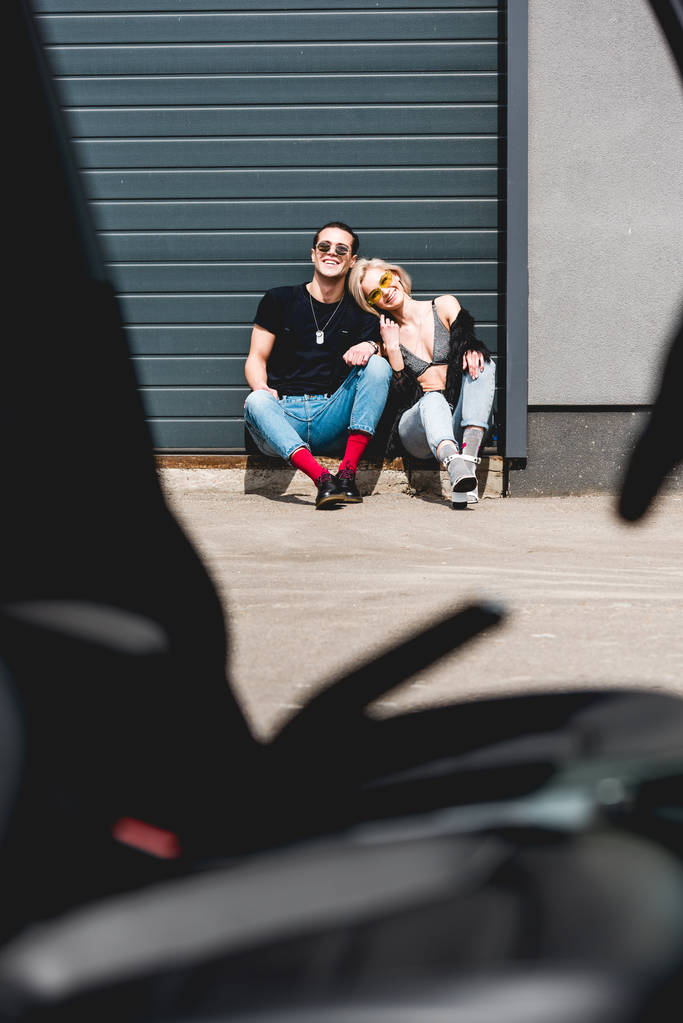 стильный мужчина и сексуальная молодая женщина улыбаются и сидят у двери гаража
 - Фото, изображение