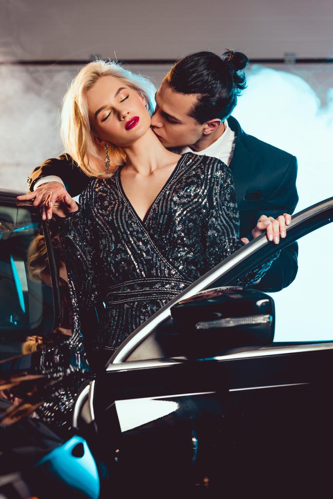 stílusos férfi csókolózás gyönyörű érzéki nő közelében autó - Fotó, kép