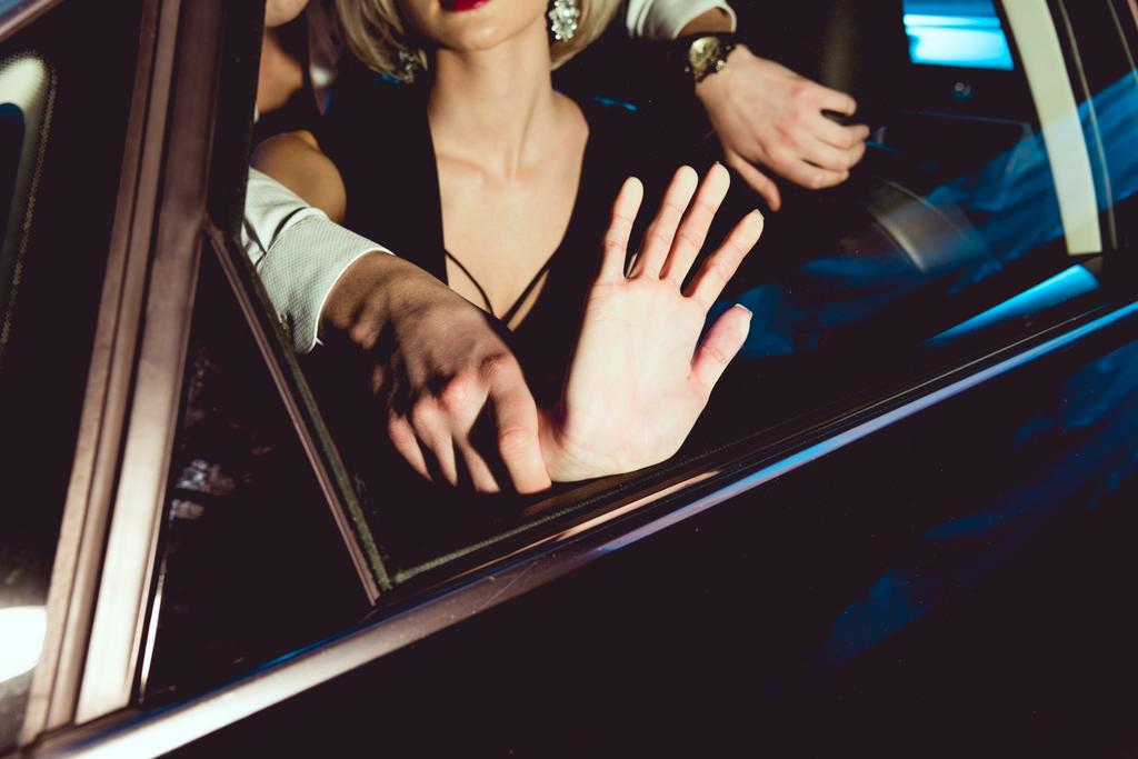 Vista recortada del hombre abrazando a la joven con la mano en la ventana en el coche
  - Foto, imagen