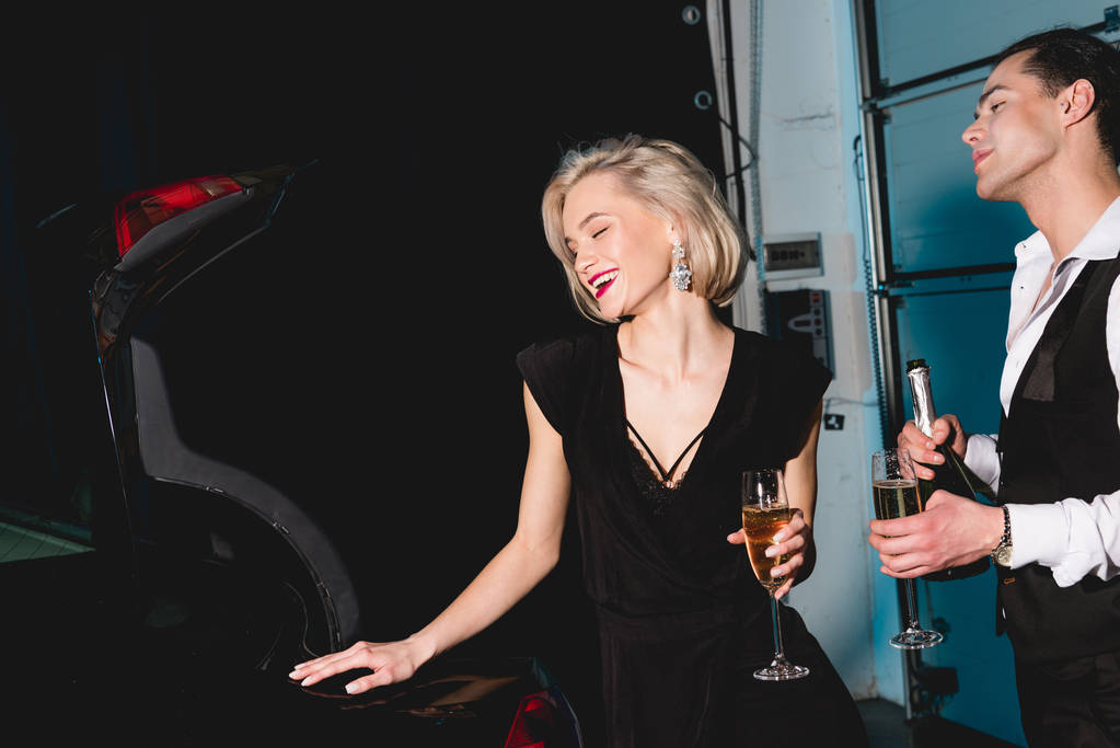 homme élégant et jeune femme heureuse avec des verres de champagne près de la voiture
  - Photo, image