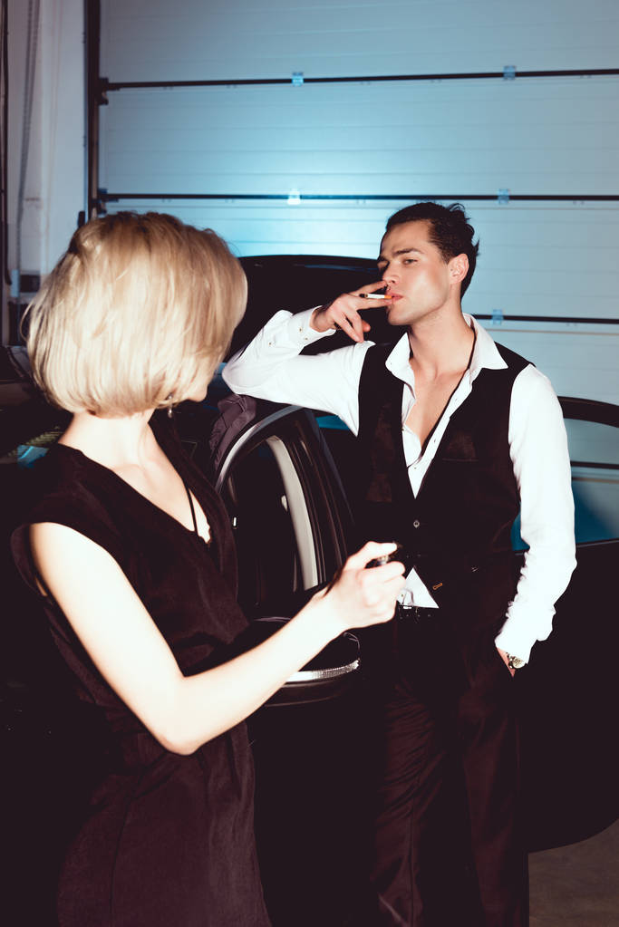 belle jeune femme à la mode tenant plus léger tandis que bel homme fumant cigarette
 - Photo, image
