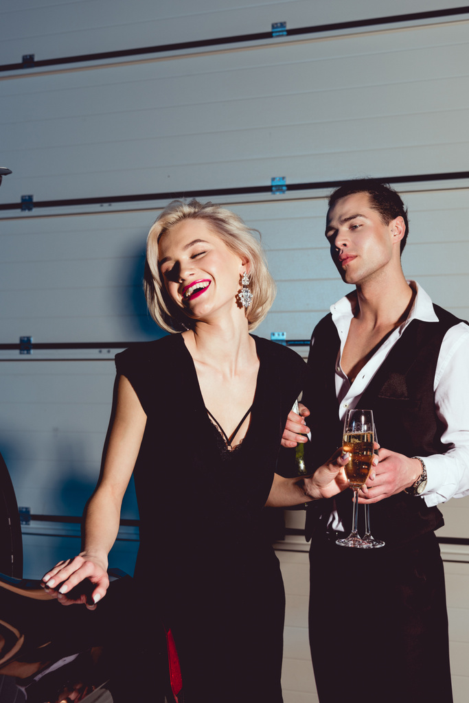 hermosa mujer joven de moda con copa de champán riendo cerca de hombre guapo
  - Foto, Imagen