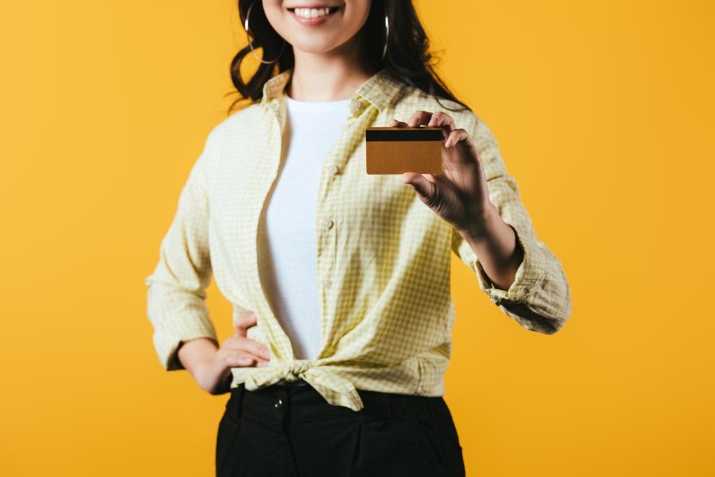 vista recortada de la mujer sonriente con tarjeta de crédito, aislado en amarillo
 - Foto, Imagen