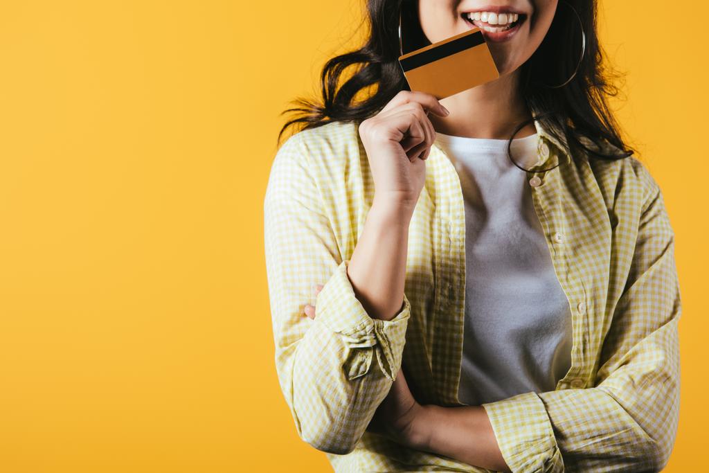 abgeschnittene Ansicht einer brünetten Frau mit Kreditkarte, isoliert auf gelb - Foto, Bild