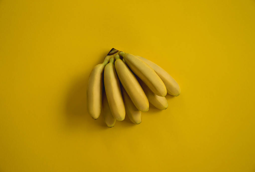 Yellow bright ripe bananas lie on a yellow background. Summer ye - Photo, Image