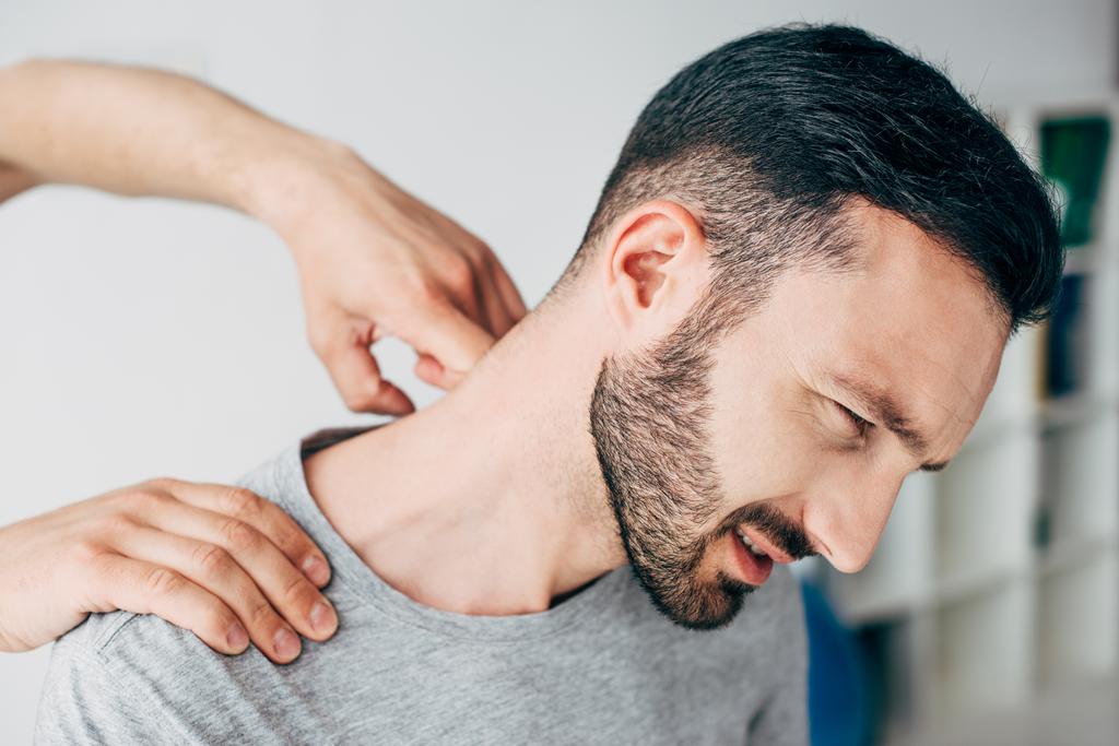 Хиропрактик массирует шею бородатого человека в больнице
 - Фото, изображение