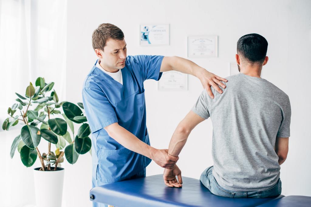 Fizjoterapeuta masowania ramienia pacjenta na stole do masażu w szpitalu - Zdjęcie, obraz