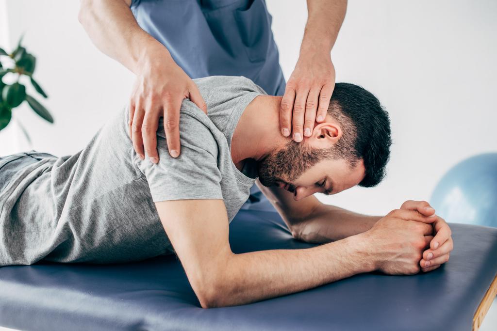 chiropractor massaging shoulder and neck of man on Massage Table in hospital - Photo, Image