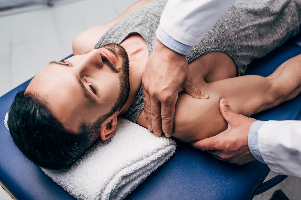 quiroprático massageando ombro de homem bonito na mesa de massagem no hospital
 - Foto, Imagem