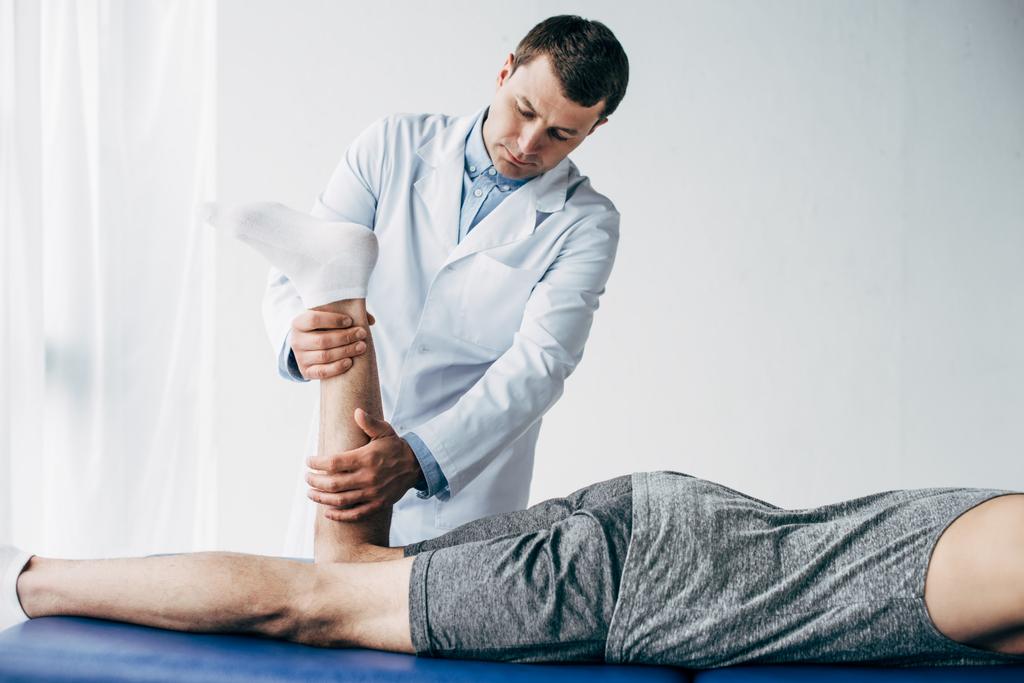 Fisioterapeuta estirando la pierna del paciente en el hospital
 - Foto, imagen