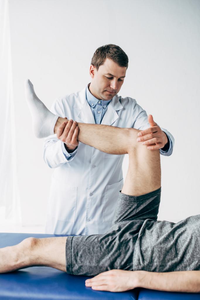 Schöne Physiotherapeutin streckt Bein einer Patientin im Krankenhaus - Foto, Bild
