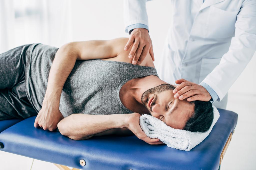 chiropraktik masírování krku člověka ležícího na masážním stole - Fotografie, Obrázek