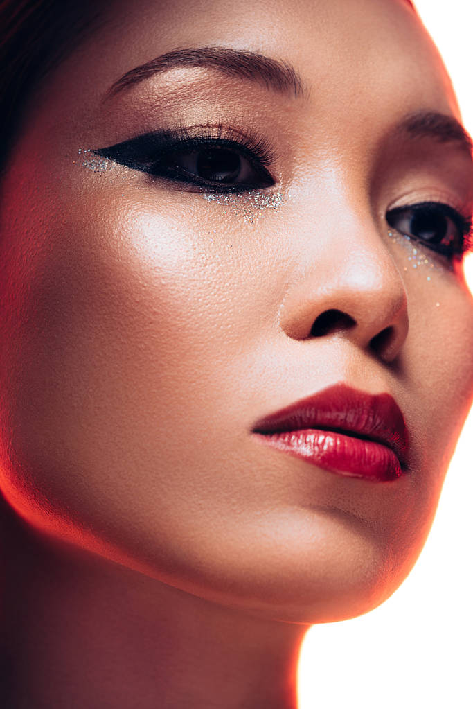 krásná asijská žena s make-upem v červeném světle, izolovaná na bílém - Fotografie, Obrázek