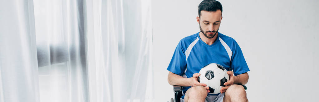 tiro panorâmico de homem em uniforme de futebol sentado em cadeira de rodas e segurando bola de futebol
 - Foto, Imagem