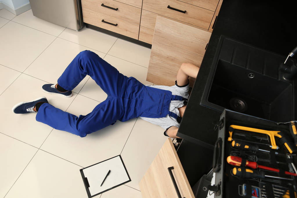 Male plumber repairing kitchen sink, above view - Photo, Image