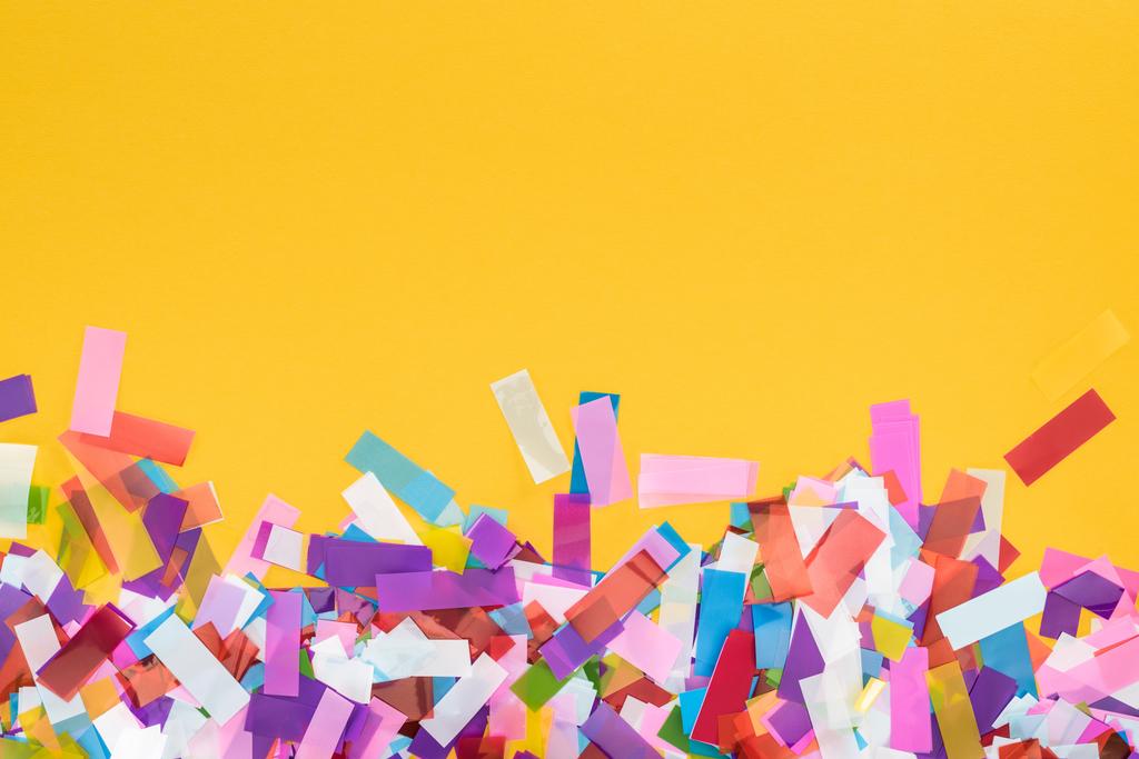 вид сверху на многоцветные конфетти на желтом праздничном фоне
 - Фото, изображение