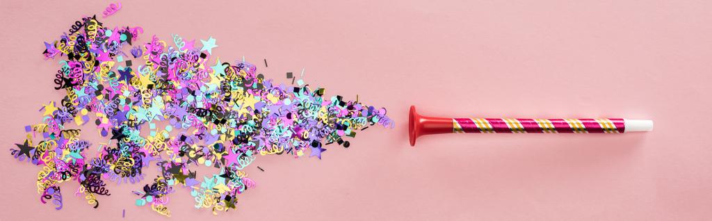 Panoramic shot of party horn with sparkling confetti on pink background - Photo, Image