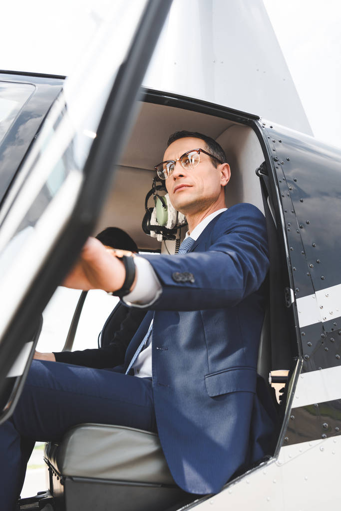 низький кут зору бізнесмена в офіційному одязі, що сидить у вертольоті кабіни
 - Фото, зображення