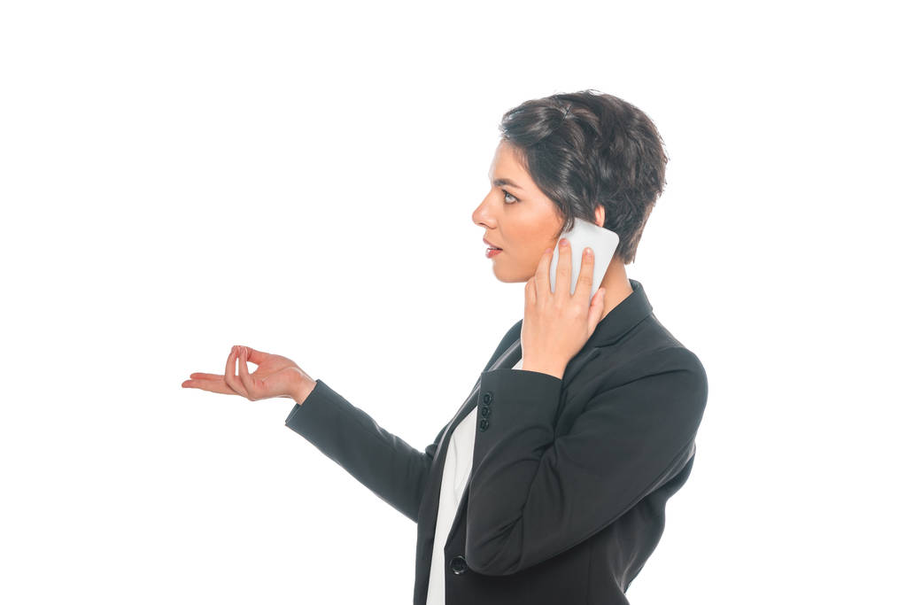 side view of pretty mixed race businesswoman using smartphone and gesturing isolated on white - Photo, Image