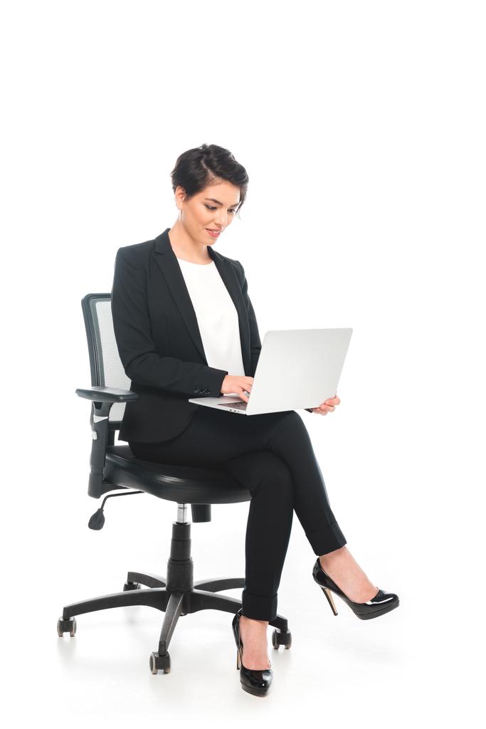 uśmiechnięta kobieta biznesmen siedzi w biurze krzesło i za pomocą laptopa na białym tle - Zdjęcie, obraz