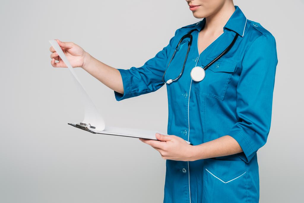 cropped shot of mixed race doctor looking at clipboard with papers isolated on grey - Photo, Image