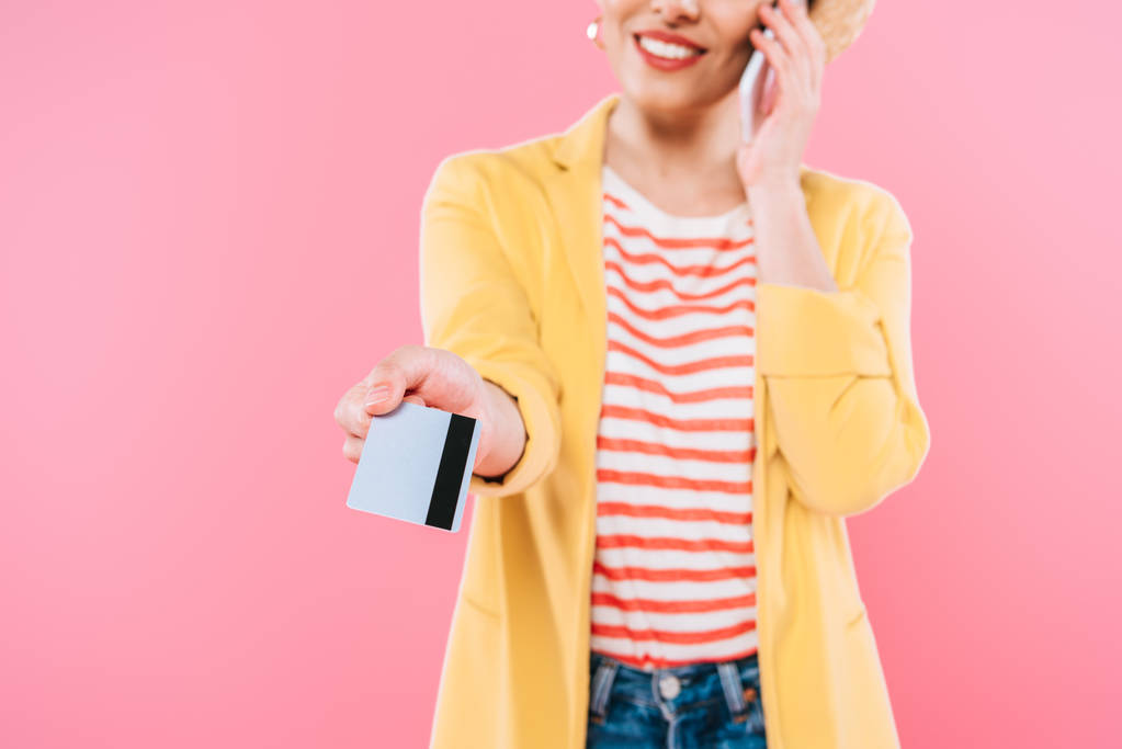 akıllı telefon üzerinde konuşan ve pembe izole kredi kartı tutan karışık ırk kadın kısmi görünümü - Fotoğraf, Görsel