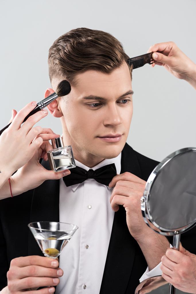 rajattu näkymä meikkitaiteilijoiden tekee meikkiä mies muodollinen kulumista holding lasi cocktail eristetty harmaa
 - Valokuva, kuva
