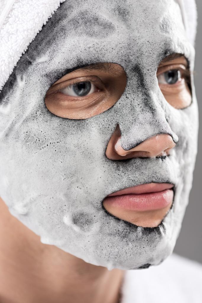 πορτρέτο του ανθρώπου με πετσέτα στο κεφάλι και αφρώδη μάσκα προσώπου κοιτάζοντας μακριά - Φωτογραφία, εικόνα