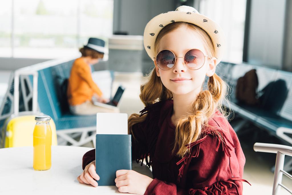 милый подросток в солнечных очках с паспортом и авиабилетом в аэропорту
 - Фото, изображение