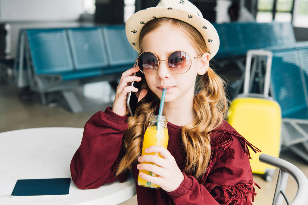 enfant préadolescent boire du jus d'orange et parler sur smartphone dans la salle d'attente
 - Photo, image