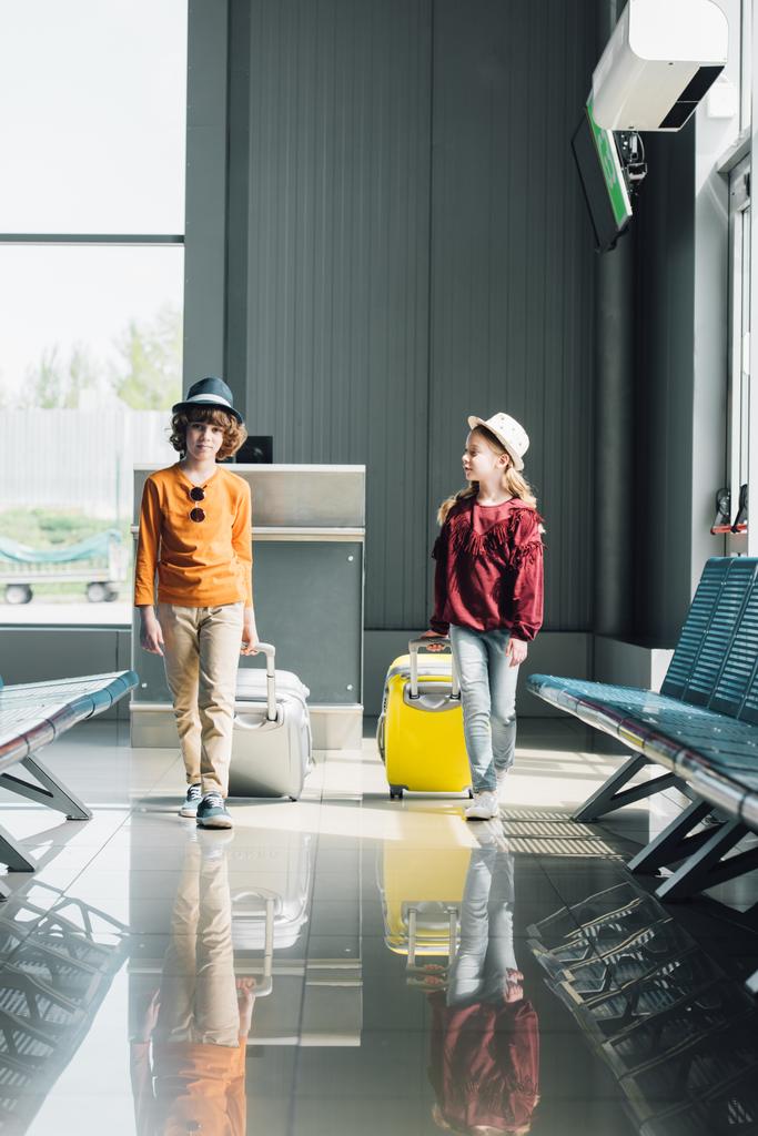 adorable preteen kids with suitcases in waiting hall in airport - Photo, Image
