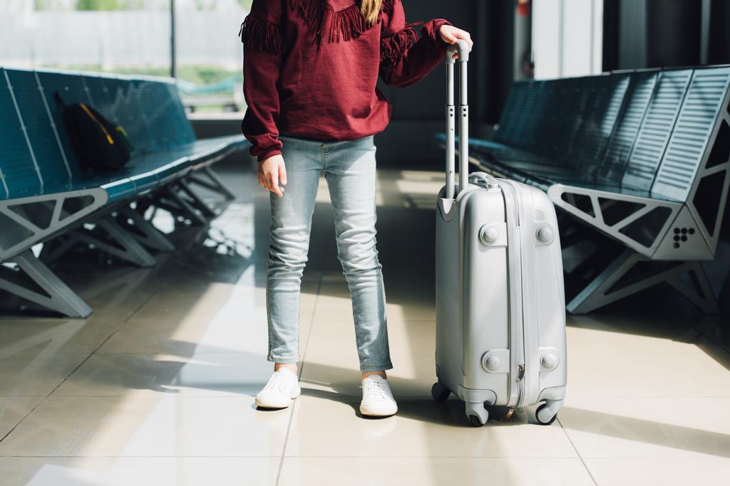 Vue recadrée du préadolescent avec valise dans la salle d'attente à l'aéroport
 - Photo, image