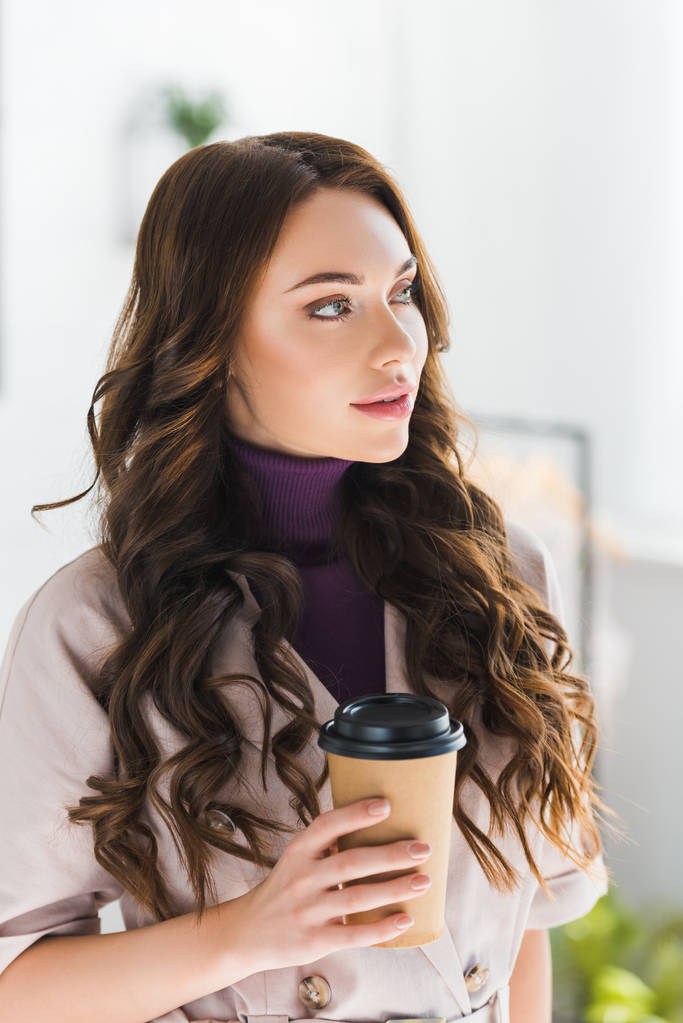 dreamy curly young woman holding paper cup with coffee  - Photo, Image