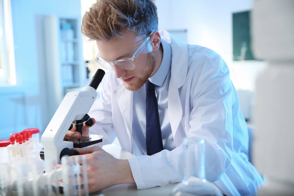 Científico masculino usando microscopio moderno en laboratorio de química
 - Foto, Imagen