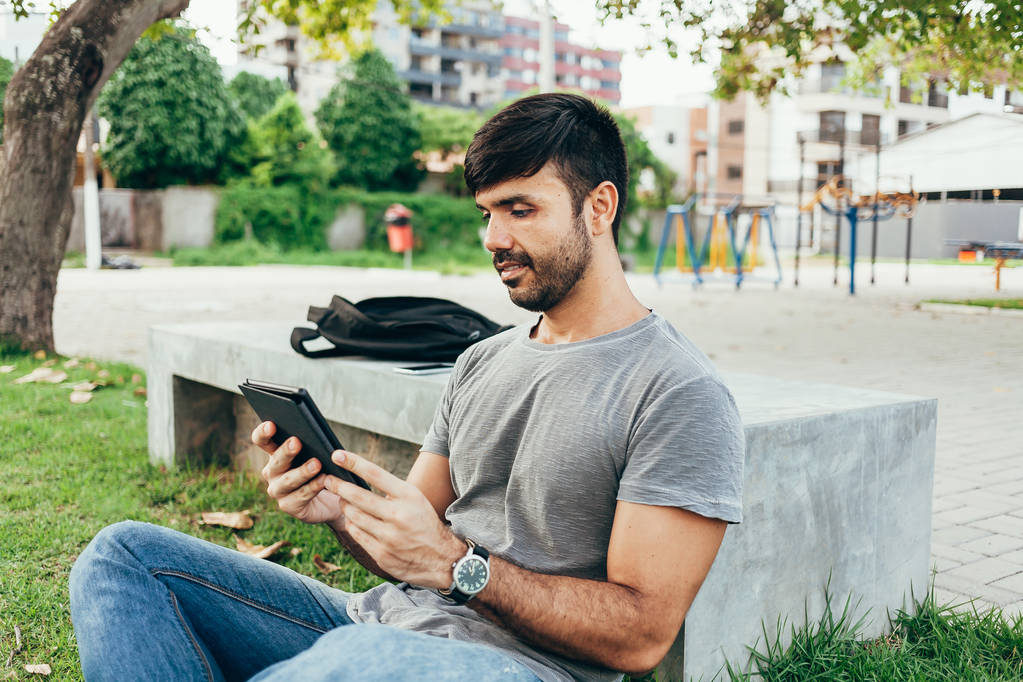 Young man reading e-book in the park - Photo, Image