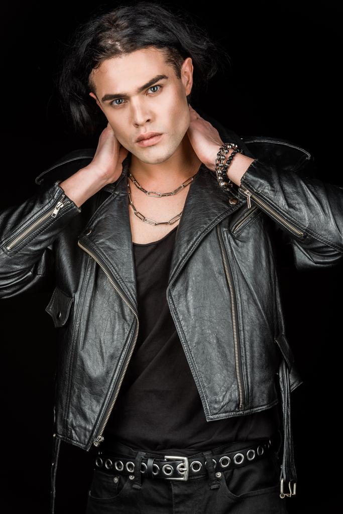 handsome man in leather jacket touching neck and looking at camera isolated on black  - Photo, Image
